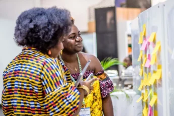 Two female Africans looking at a banner : Google for Startups Accelerator Africa 2025