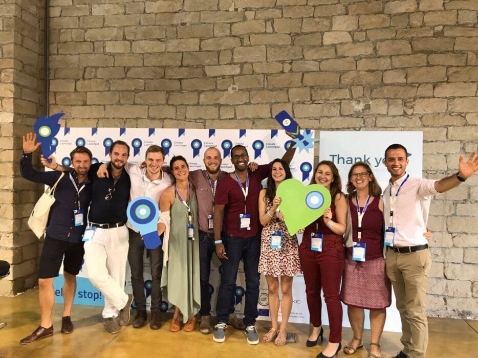 Smepaks networking group at SMEPEAKS event, diverse professionals smiling and celebrating success in a modern industrial space with branded backdrop and creative decor.