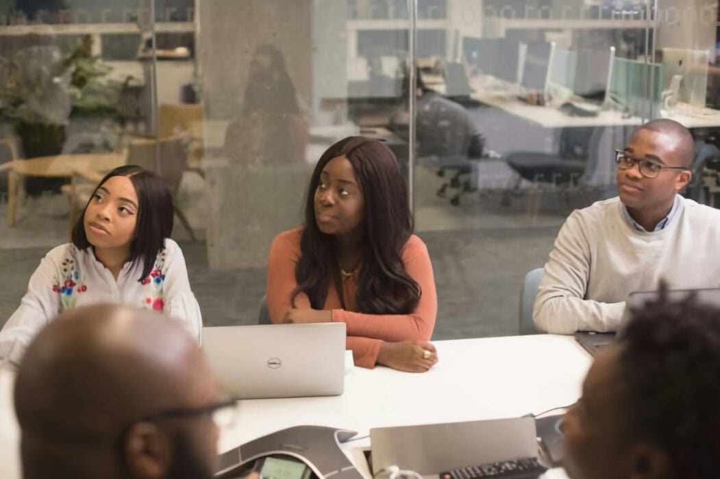 Elevated view of diverse business professionals participating in a team meeting at SMEPEAKS, using laptops and digital devices in a modern office setting for strategic planning and collaboration.