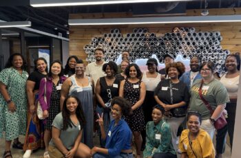 People attending a diverse networking event at SMEPEAKS, with a creative wooden wall art background, showcasing community, empowerment, and entrepreneurship in a modern collaborative space.